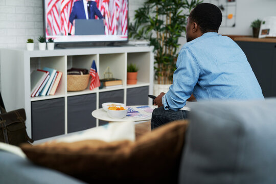 Wide image of man watching TV with American aspects