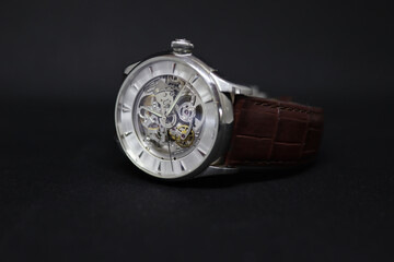 a mechanic automatic skeleton watch with leather strap, showing the inner mechanism