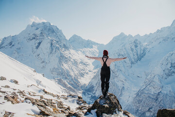 Winter holidays in the mountains. Young woman on a background of snowy mountains.