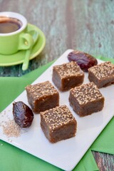 Dates tahini square sweet bites topped with sesame seeds. Served with espresso coffee.
