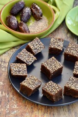 Dates tahini square sweet bites topped with sesame seeds. 

