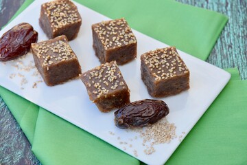 Dates tahini square sweet bites topped with sesame seeds. 
