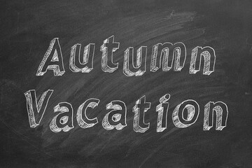 Hand drawing text "Autumn vacation" on blackboard
