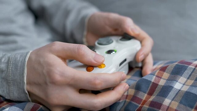 The Guy Gamer Plays Computer Games Using a Gamepad, Close-up. The Fingers Press the Buttons on the Remote Controller, Macro. Closeup of Hands and Gamepad. 