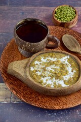 Bubur Kacang Hijau, Indonesian dessert made from mung beans cooked in coconut milk and palm sugar flavored with pandan leaves. Served on wooden bowl with tea
