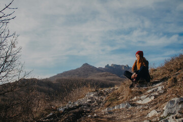 Fototapeta premium Traveler in the mountains on the background of blue sky in autumn. Sit on top.