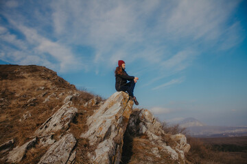 Traveler in the mountains on the background of blue sky in autumn. Sit on top.