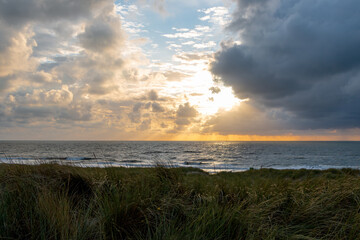 Sunset on the North Sea near the town of Petten, with dark colored clouds and an orange setting sun