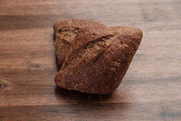 Zwei dunkle eckige Brötchen auf einem hölzernen Hintergrund