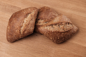 Zwei kusprige braune Frühstück-Brötchen auf einem Holzbrettchen