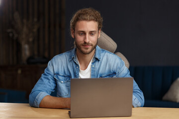 Portrait of smiling handsome long haired curly man using laptop for a online meeting in video call. Working from home. Communication online with colleagues and freelancers and video conference.