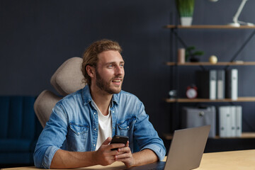 Portrait of smiling handsome long haired curly man using laptop for a online meeting in video call....