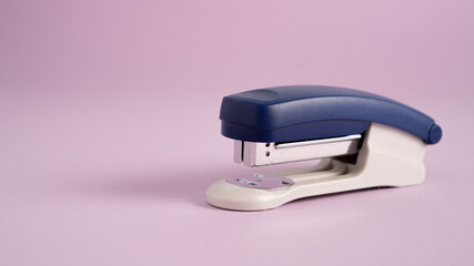 Blue stapler isolated on a purple background. Office supplies. Stapler, staple, paper, cardboard, office equipment