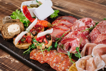 A dish with variety of smoked meat, salamy, ham on wooden background