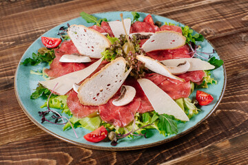 A dish with red fish, cheese and mushrooms on wooden background