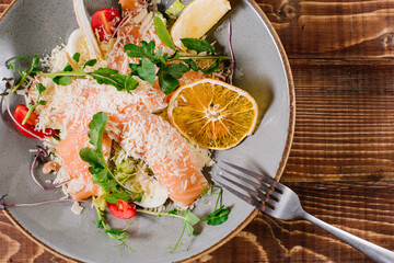 A dish with salmon, vegetables and herbs on wooden background