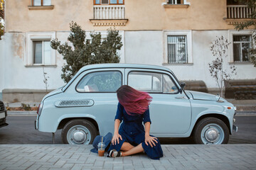 Woman with pink hairstyle sitting on car background. Old vintage automobile on street. New place and new emotion idea