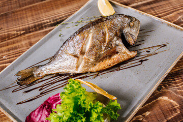 Smoked dorado fish with herbs on wooden background