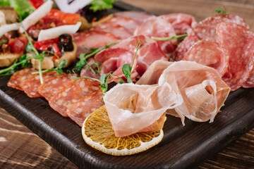 A dish with variety of smoked meat, salamy, ham on wooden background