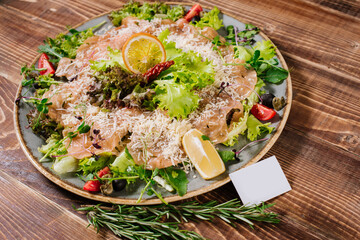 A dish with salmon, vegetables and herbs on wooden background