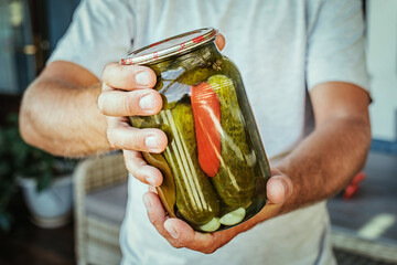 canning cucumbers, male hands holding a jar of cucumbers
