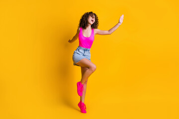 Fototapeta na wymiar Full length profile photo of attractive youngster curly lady dance disco students party skinny figure wear pink tank top denim mini skirt shoes isolated bright yellow color background