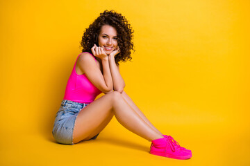 Full length profile photo of attractive pretty flirty lady summer chill sit floor beach dreamer peaceful vacation wear pink singlet denim skirt sneakers isolated shine yellow color background