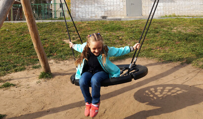Child girl riding a swing and laughing