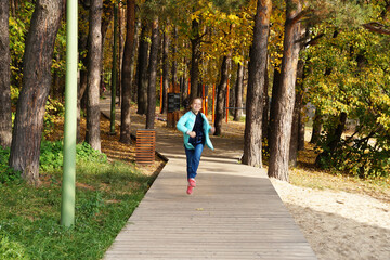 child girl running along the wooden path in the park