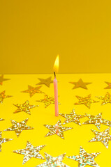 Single pink party candle, stars gliter on the bright yellow background.Vertical image