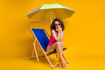 Photo portrait of cute girl sitting in blue lounge chair under parasol holding head with hands...