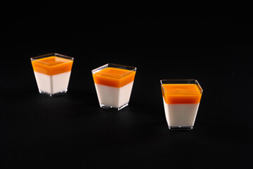 Glasses with creamy panna cotta with orange topping.