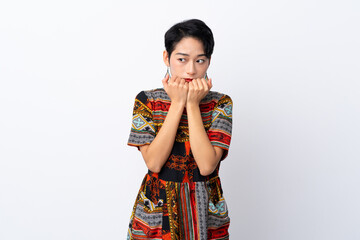 Young Asian girl with a colorful dress over isolated white background nervous and scared putting hands to mouth