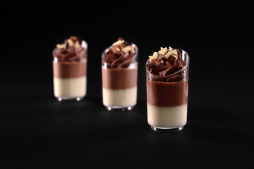 Glasses with layered panna cotta mousse isolated on black.