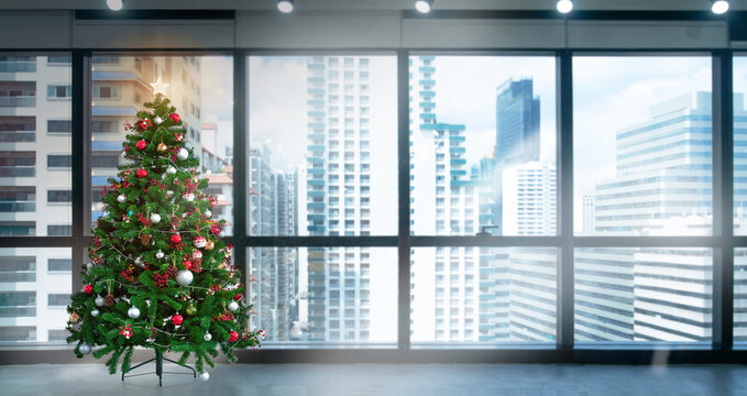 Christmas tree in modern office near big window and building view in city