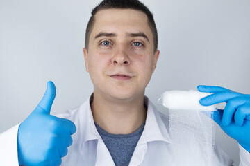 A traumatologist in blue medical gloves holds a wound bandage. The concept of providing medical care for bruises, fractures and injuries