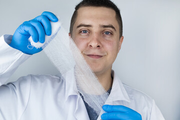 A traumatologist in blue medical gloves holds a wound bandage. The concept of providing medical care for bruises, fractures and injuries