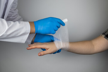 The traumatologist applies a bandage to the patient's wrist. The concept of helping with fractures and sprains. The technique of applying a cruciform bandage.