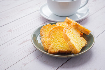 Crispy butter toast and a white coffee cup on wooden table with space for text