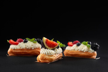 Homemade eclairs with white cream and berries.
