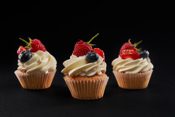 Tasty mufins with berries, isolated on black background.