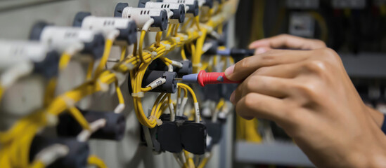 Obraz premium Electricians hands testing current electric in control panel.