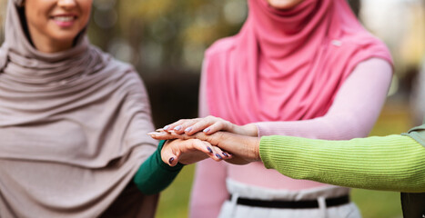 Obraz na płótnie Canvas United Muslim Women In Hijab Holding Hands Standing Outdoors, Cropped