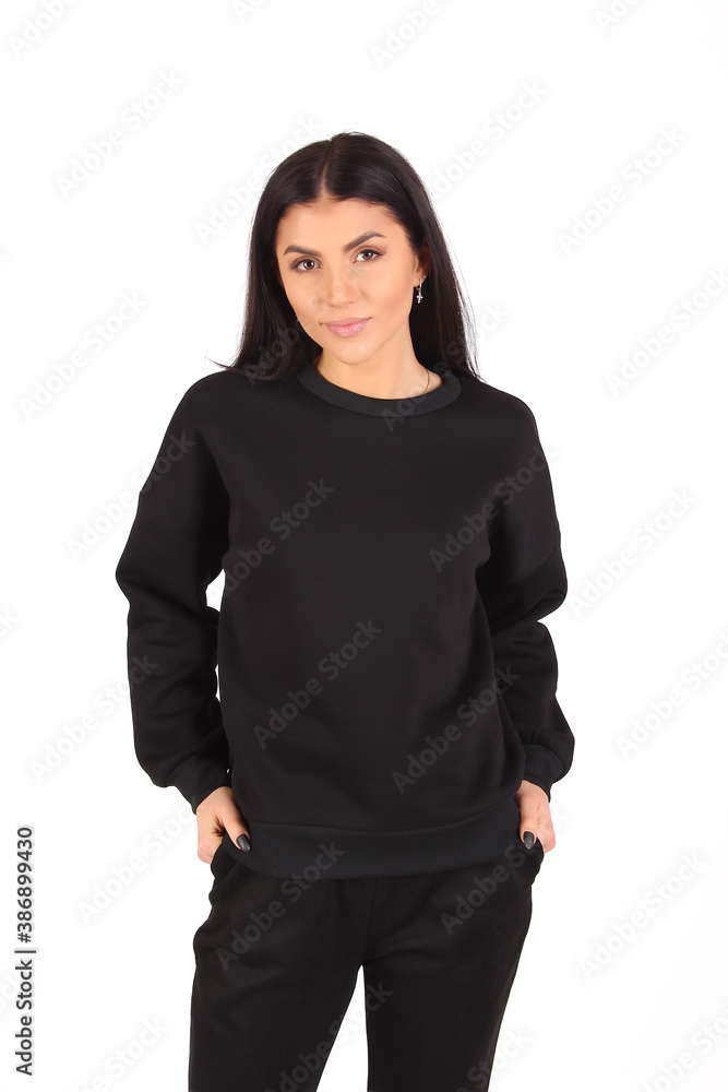 Wall mural Young hipster girl girl wearing white and black cotton sweatshirt with area for your logo, mock-up of white women hoodie, white wall in the background with copy space for your design or content