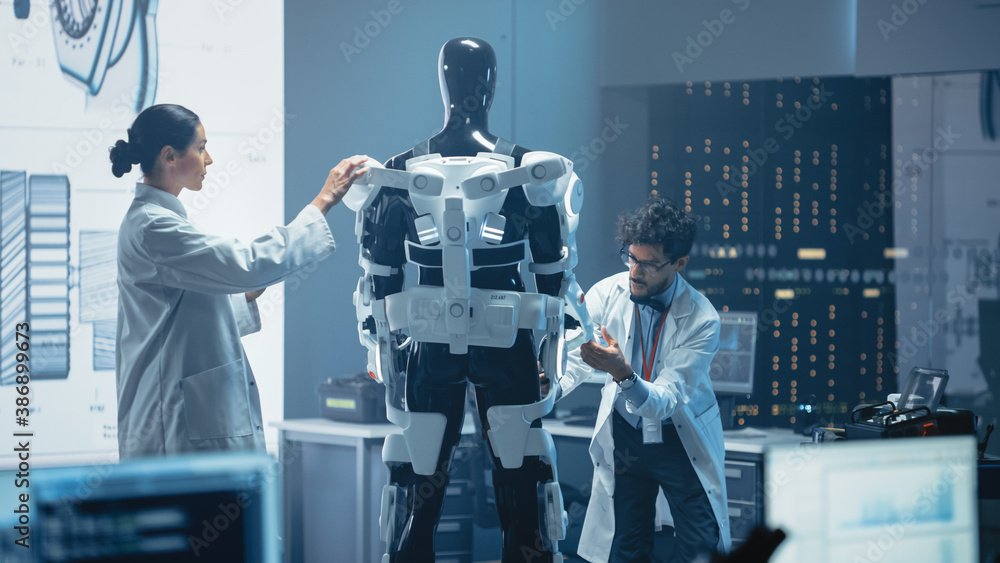 Poster Chief Analyst Uses Computer, Female Engineer and Top Male Scientist Work on a Bionics Exoskeleton Prototype. Designing Powered Exosuit to Help Disabled People, Hard Labor Workers