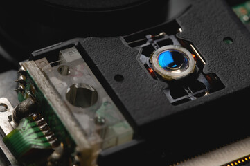 Macro close-up of a DVD drive head with a laser lens on the background of microcircuits. Electronics background