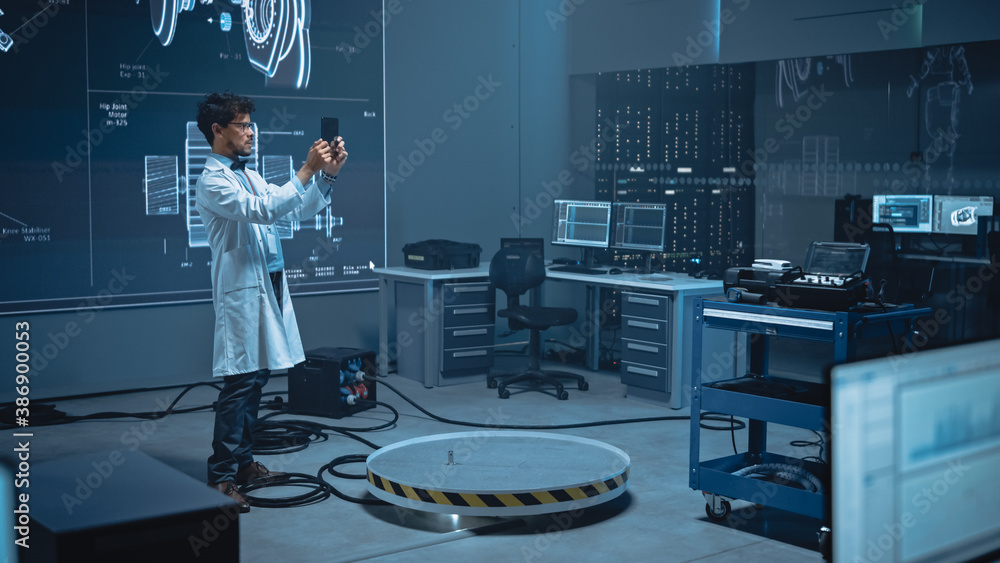 Leinwandbilder In High-Tech Development Laboratory: Engineer Uses Digital Tablet Computer with Augmented Reality Software to Analyse Content. Modern Facility with Big Screens Showing Industrial Design.