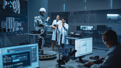 In Robotics Development Laboratory: Engineers and Scientists Work on a Bionics Exoskeleton Prototype with Person Testing it. Designing Wearable Exosuit to Help Disabled People, Hard Labor Workers