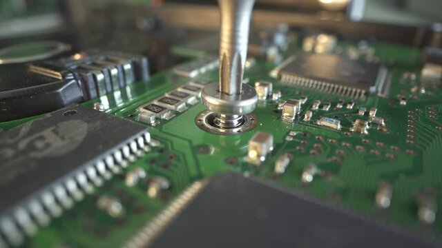 The master pulls off and than twists the hard drive screw with screwdriver before start reair HDD. Macro shot of many micro chip. Green electronic board. Capacitor, processes in frame. Repair computer