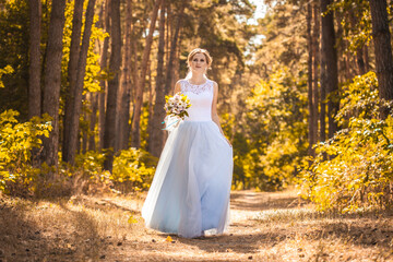 Obraz na płótnie Canvas happy bride with a bouquet is walking the green park